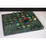 A marble solitaire board together with associated marbles.