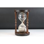 Large Glass Sand Timer held on a Mahogany Circular Frame with turned supports, 24cm high