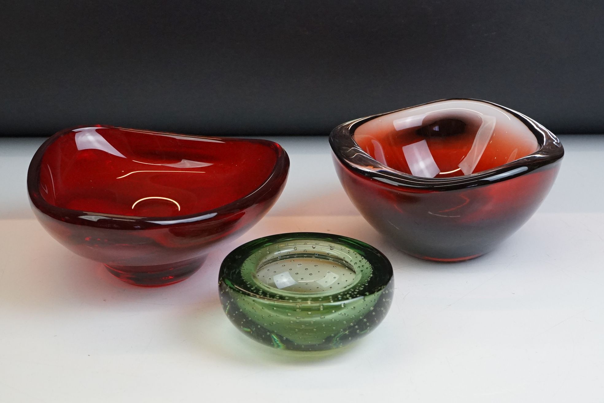 Whitefriars Green Glass Bubble Control Lipped Bowl, 10cm diameter together with two Red Glass Bowls