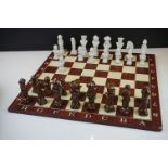 A set of ceramic chess pieces together with wooden chess board.