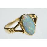 Opal 18ct yellow gold ring, the oval cabochon cut previous white opal displaying violet, blue,