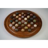 A turned wooden solitaire board complete with polished semi precious stone marbles.