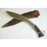 A vintage full size kukri knife with wooden handle and fullered steel blade, complete with
