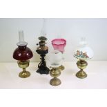 Five late 19th / early 20th century oil lamps to include a brass example with etched cranberry glass