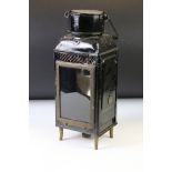 Early 20th century metal lantern with a black painted case and carry handle, raised on four brass