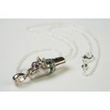 Silver dog whistle with ruby eyes and emerald collar, on silver chain