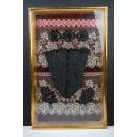 Late 19th / early 20th century doll's corset, in a framed presentation with beadwork flowers on an