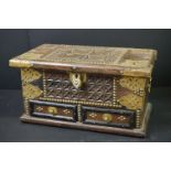 An Indian wooden box with decorative brass fittings, two drawers to the front with hinged lid.