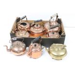 A collection of seven antique copper kettles together with a brass example.