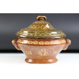 Slipware Terracotta twin handled Tureen & Cover, of oval form, with repeated scrolling design,