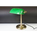 Brass bankers lamp with green glass pivoting shade, reeded brass support, raised on a circular base.