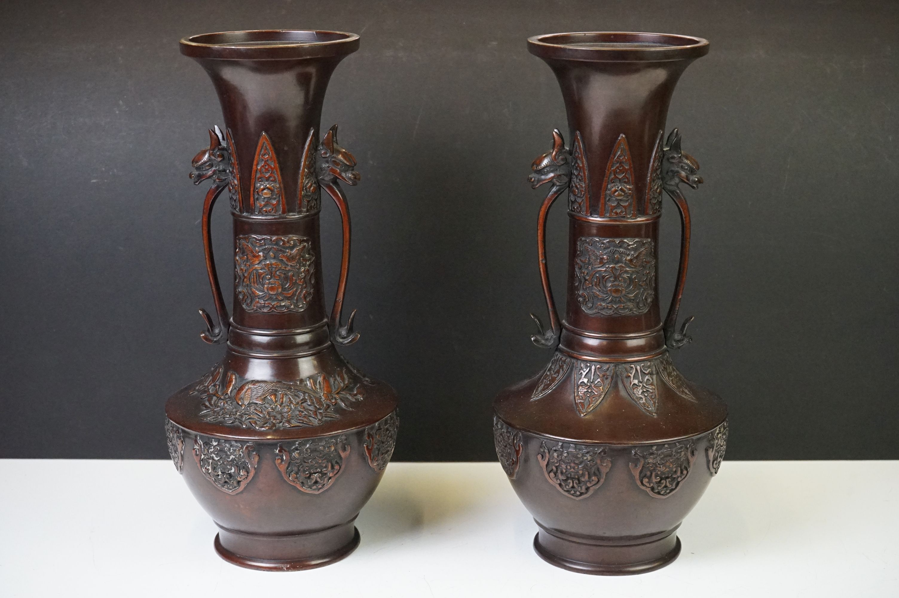 Near pair of Japanese bronze twin-handled bottle vases, with relief ornithological decoration and