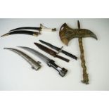 A collection of three sheathed daggers to include two arabic examples together with a brass axe.