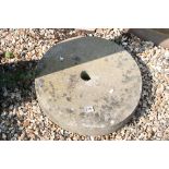 A large stone mill wheel, measures approx 50cm in diameter.