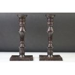 Pair of metal candlesticks raised on square screw-in drip pan bases, approx 20cm high