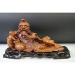 Chinese carved hardwood sculpture of a recumbent man with child, raised on a hardwood base of