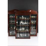 A large collection of souvenir spoons contained within three collectors cabinets.