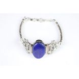 A decorative silver bracelet set with large lapis lazuli cabochon.