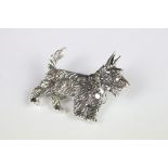 A silver dog brooch set with a ruby eye.