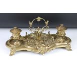 Brass standish with cast Gothic decoration, twin inkwells with glass liners (one matched), pen rests