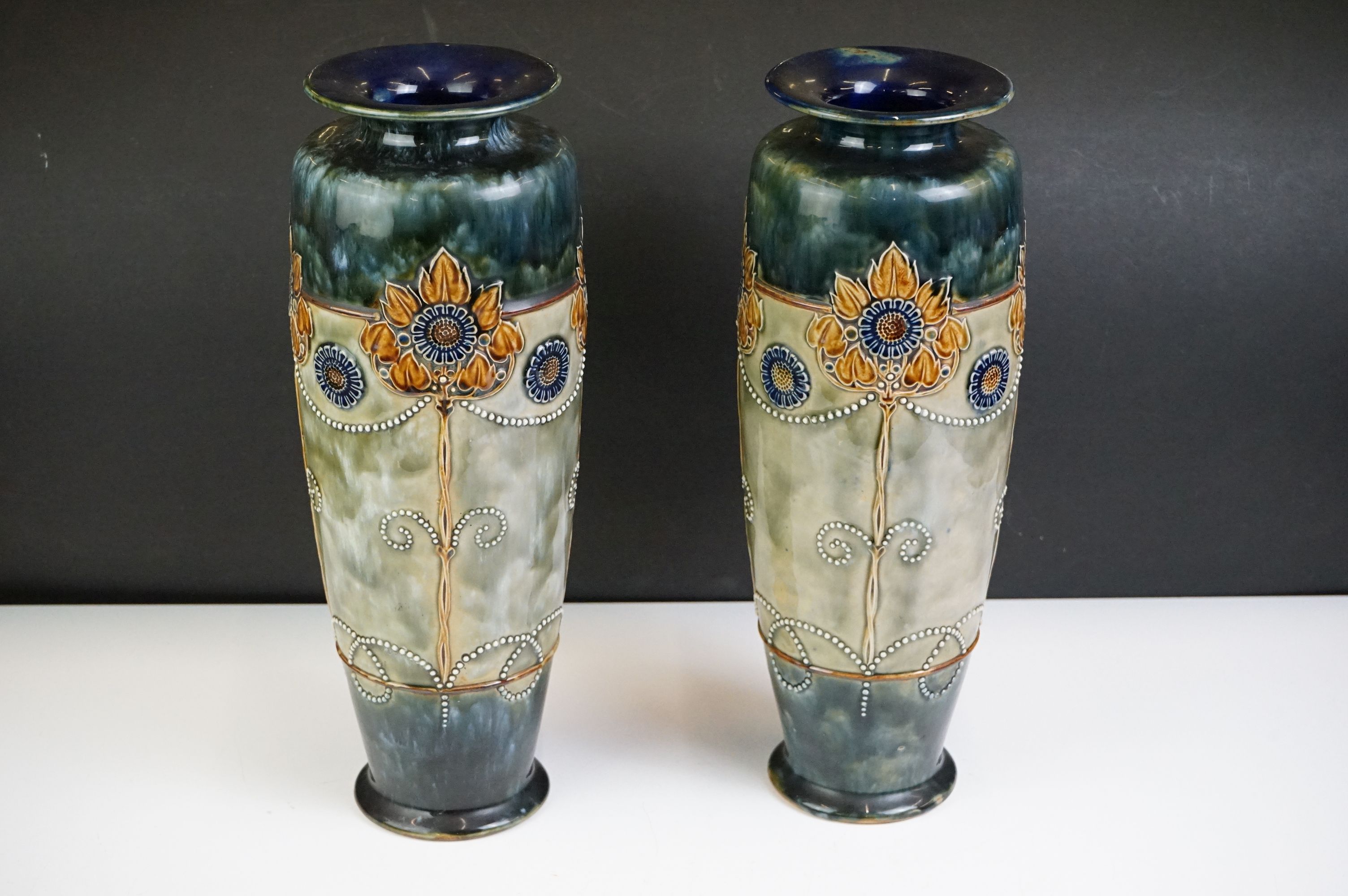 Pair of Royal Doulton Art Nouveau vases of tapering form, relief decorated with stylised flowers,