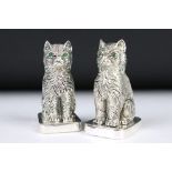 A pair of silver plated cat condiments with emerald eyes.