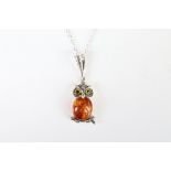 A silver and amber owl pendant necklace on silver chain.