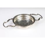 A sterling silver twin handled tea strainer, assay marked for Sheffield.