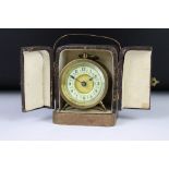 An antique brass cased travel clock with decorative dial complete with travel case.