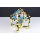 A contemporary desktop globe made with semi precious stones and mounted on brass framework.