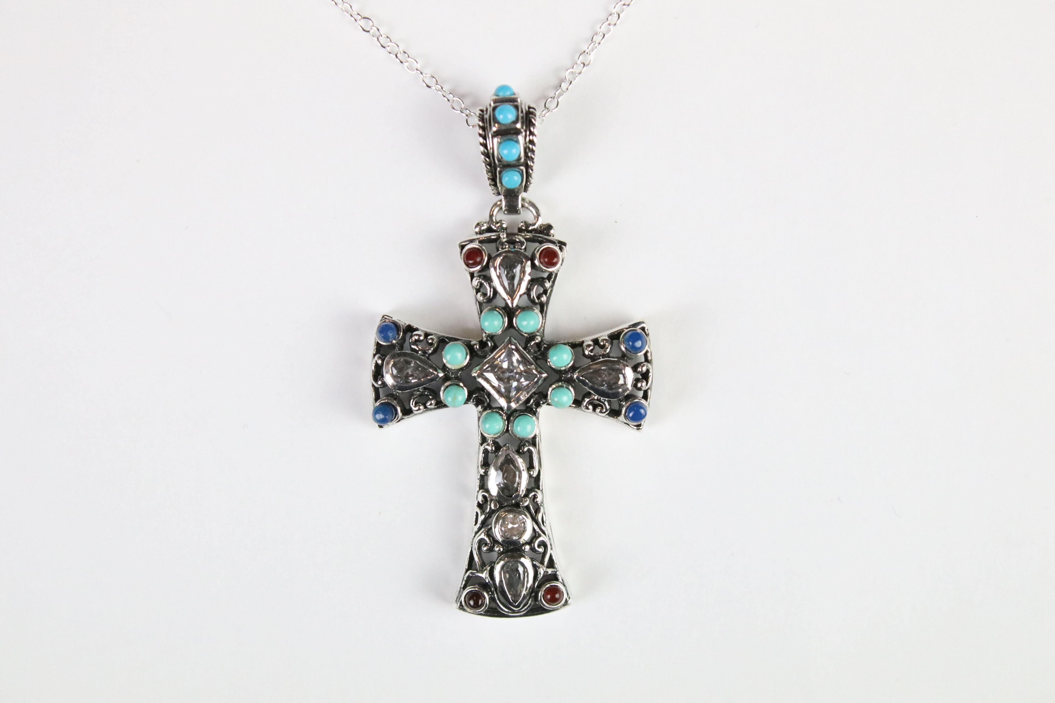 A silver pendant cross set with turquoise and ruby cabochons.