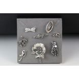 Collection of silver and white metal brooches including large silver cat brooch.