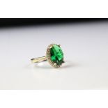 a gold plated on silver dress ring with faux emerald surrounded by CZS.