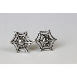 A pair of silver spider web stud earrings.