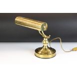 Brass bankers style lamp having a round base with adjustable arm and cylindrical brass shade to