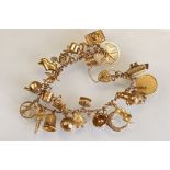 9ct gold curb link charm bracelet, twenty-six 9ct gold charms, padlock clasp, safety chain