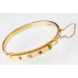 Edwardian diamond and ruby 15ct yellow gold hinged bangle, the central round old cut diamond