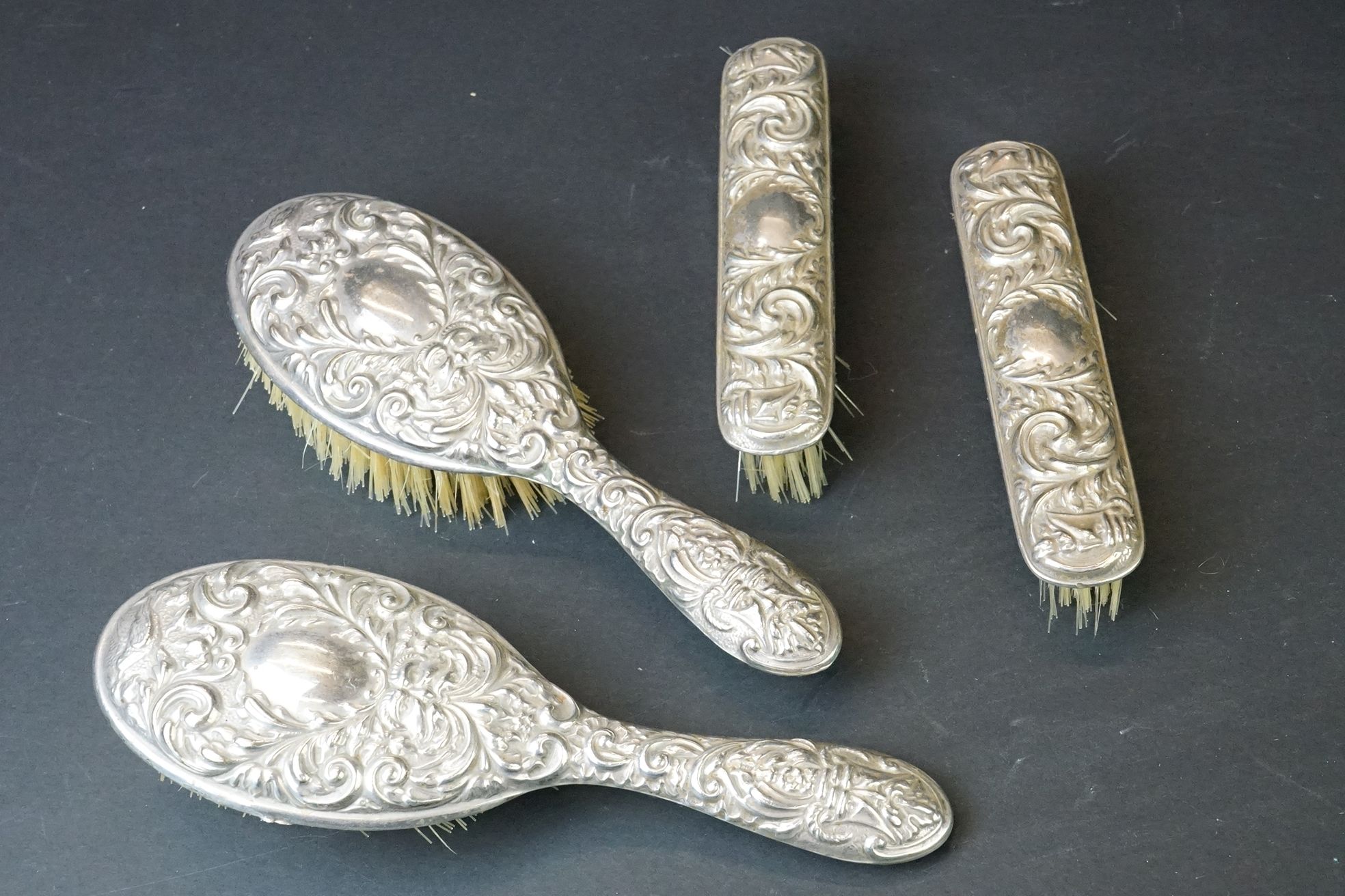 Mid 20th C silver mounted four-piece dressing table brush set with repousse Gothic-style decoration,