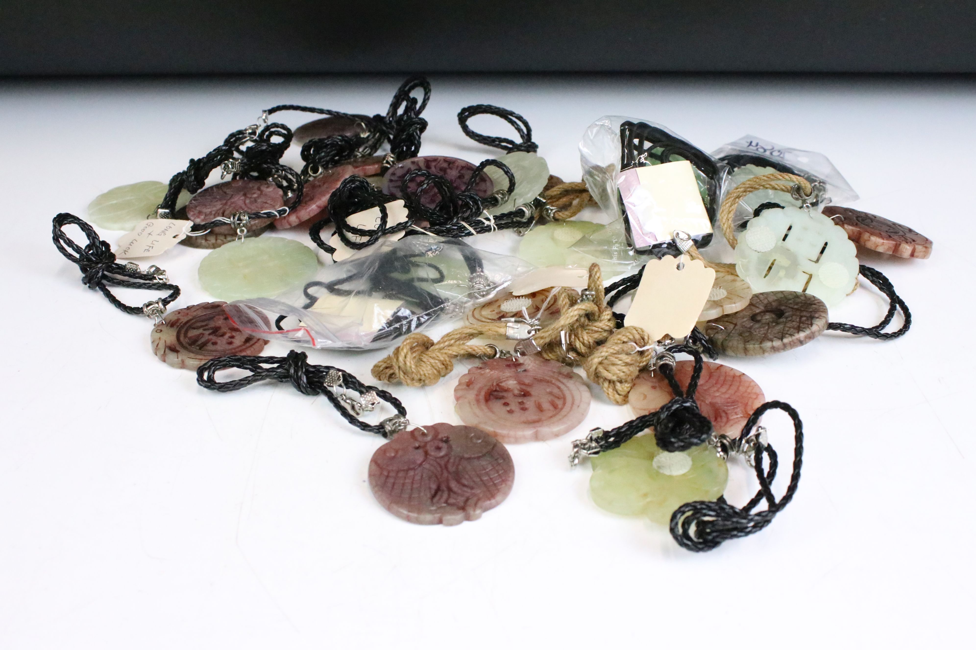 A collection of twenty seven carved jade pendants on leather / hessian necklaces.