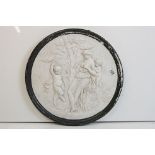 Reconstituted stone circular wall plaque depicting a classical scene of a maiden and two putti.
