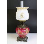 An antique oil lamp having floral decoration to base and opaque shade and scrolled feet. Measures