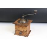 An antique coffee grinder set within wooden case with lower coffee drawer.