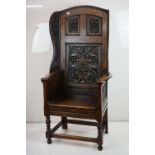 18th / 19th Oak Wingback Lambing Chair with arched top, the back carved with panels of foliage,