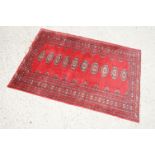 Eastern Red Ground Wool Rug decorated with a row of ten guls within a border, approx. 190cm x 130cm