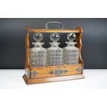 An antique oak tantalus with silver plated mounts with three glass decanters.