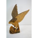 Carved wooden eagle statue carved with out stretched wings with painted detailing raised on a wooden