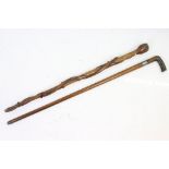 Two sticks including hand carved with claw and ball handle with two snakes climbing the shaft and