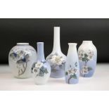 Four Royal Copenhagen vases of varying shapes , each decorated with florals to a blue ground.