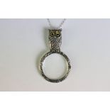 A silver owl shaped magnifying pendant necklace