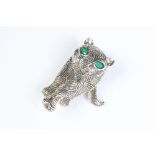 A silver art deco style cat brooch set with emerald eyes